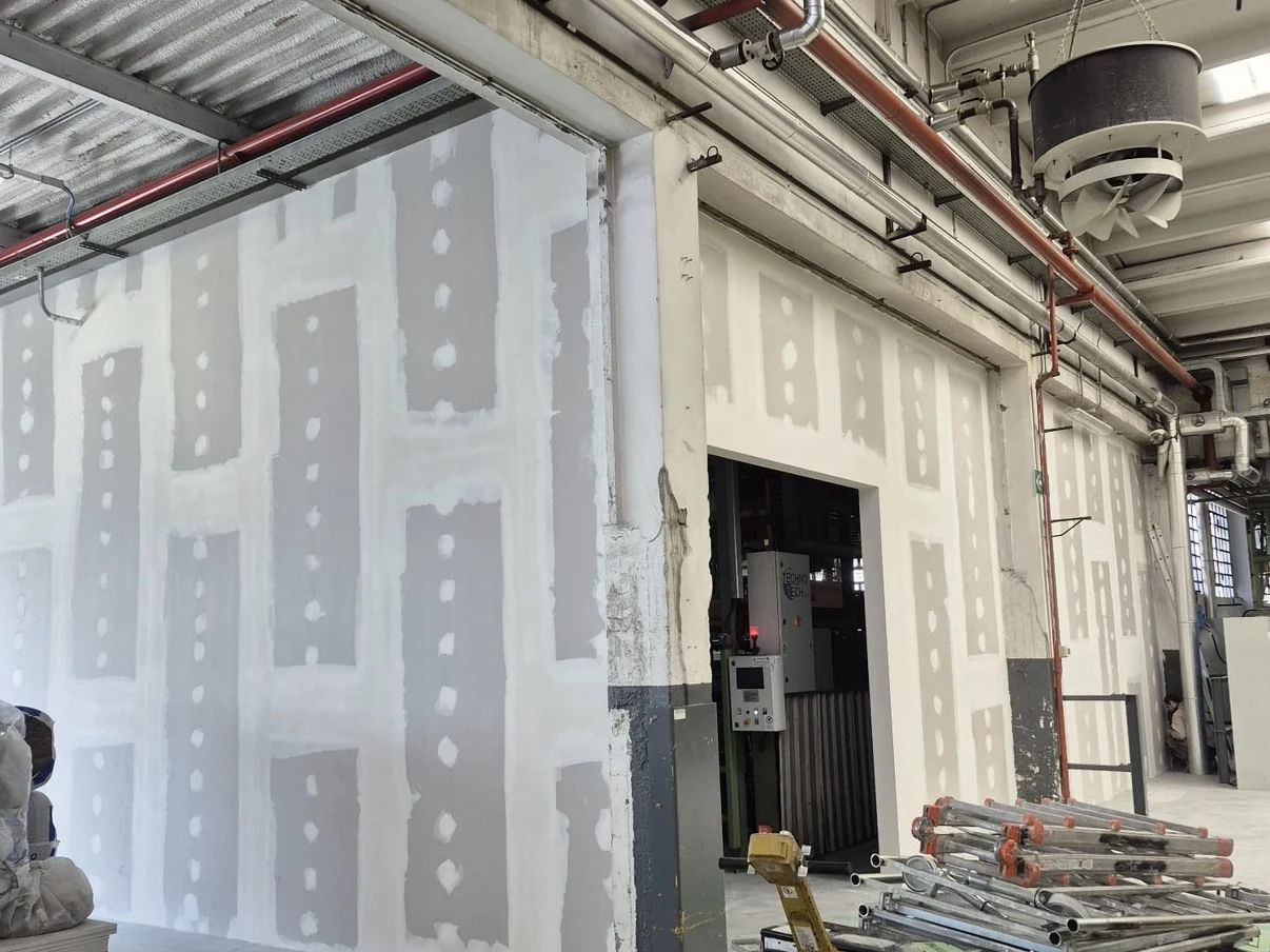 Pareti in cartongesso in fase di finitura all’interno di un ambiente produttivo